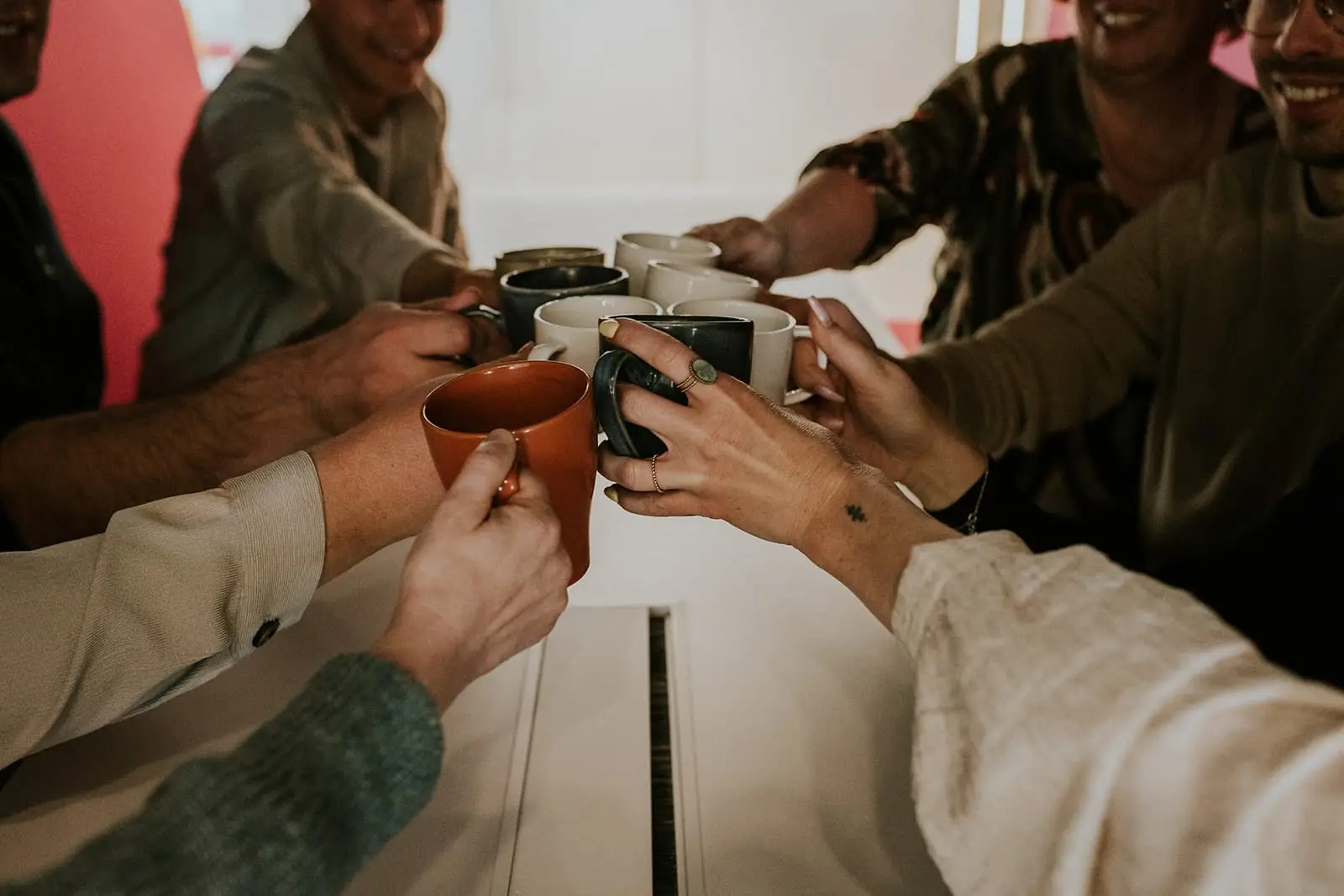 Collega's toosten met koffiemokken boven de vergadertafel